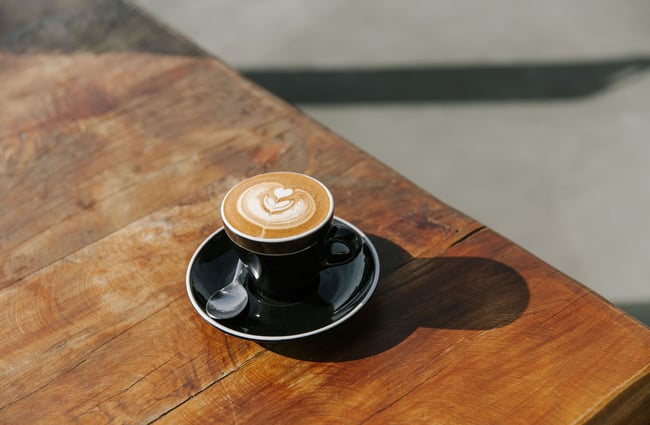 A close up of a flat white on a table on a very sunny day at the Greedy Cow Café in Tekapo.