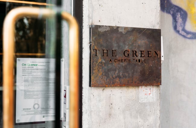 A sign that says 'The Green' on a concrete wall.
