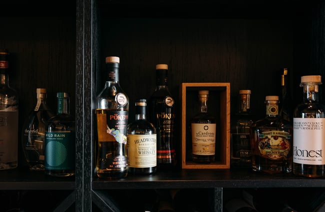 Bottles of liquor lined up on a black shelf.