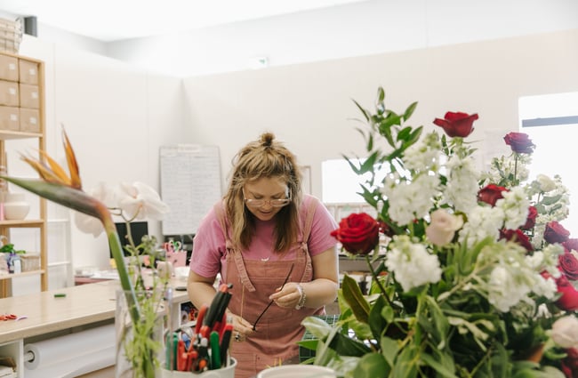 A florist in a pink apron making bouquets of flowers.