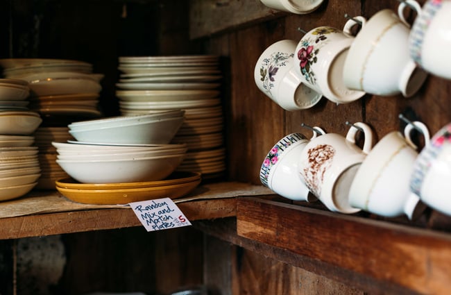 Cups and saucers on display on wooden shelves.
