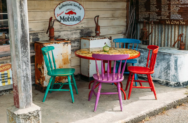 Colourful chairs around a wooden round table.