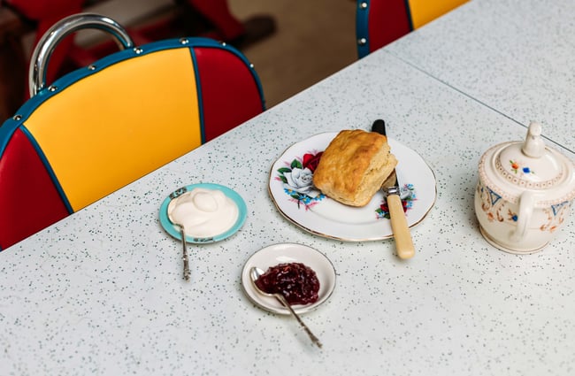 A close up of cream, jam and a scone on a formica table.