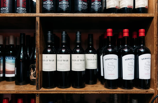 A close up of wine bottles on shelves.