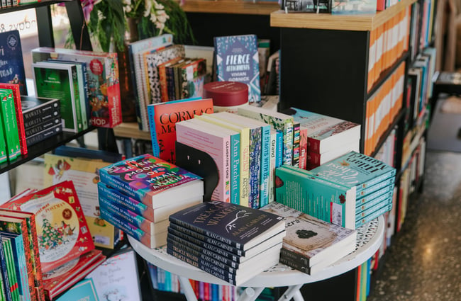 Books stacked on top of a small table at The Next Chapter, Wānaka.