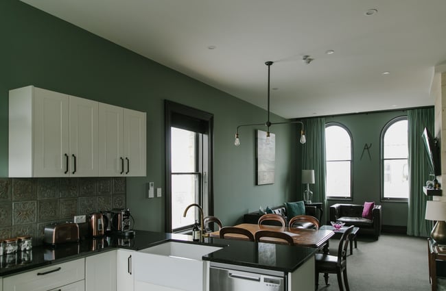 The green painted walls of a living and kitchen room.