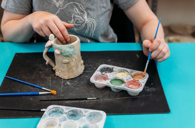 Hands painting a ceramic cup.