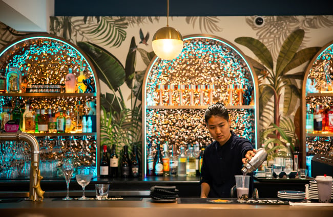 A staff member working behind a colourful bar.