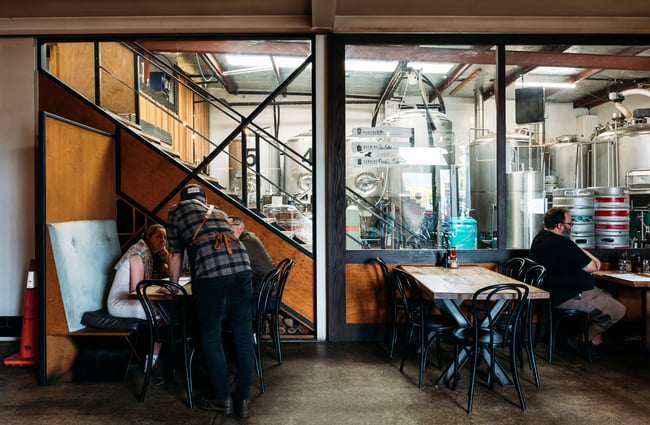 A bar with a glass wall looking into a brewery.