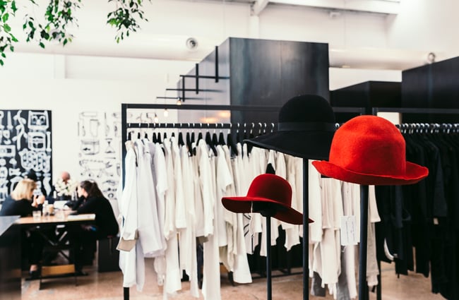 Red hats by clothing racks.