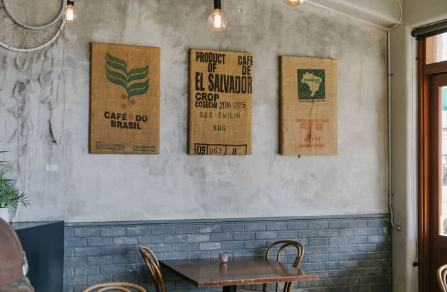 Old coffee bean bags mounted on the wall above table at The Smoking Barrel, Motueka Tasman.