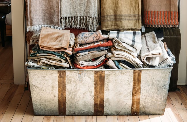 Close up of linen and cotton towels in a vintage metal trunk in The Workroom.