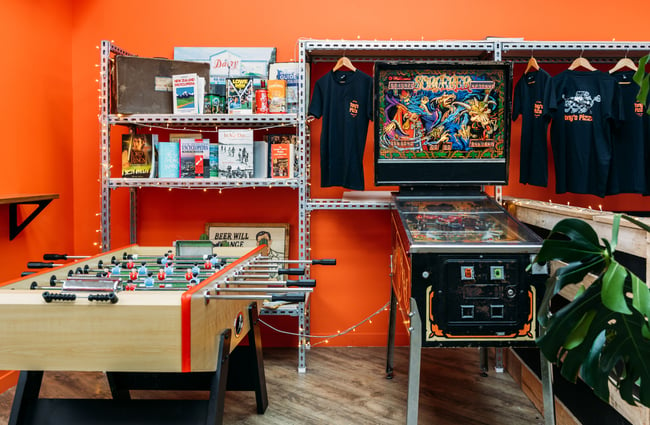 Foosball and arcade game against an orange painted wall.