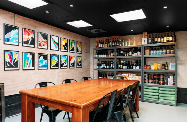 A large table inside a room decorated with art and shelves of wine.
