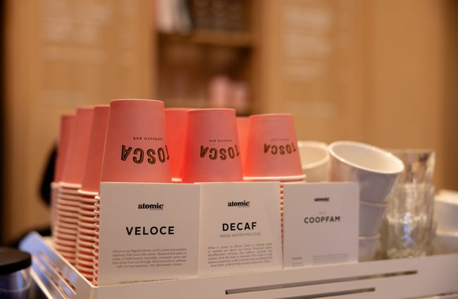 Pink Tosca takeaway coffee cups lined up on coffee machine