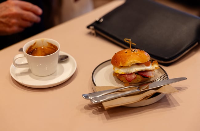 Bacon and egg bun and black coffee on table