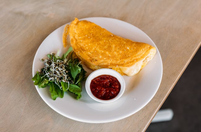 Omelette, relish and salad greens on a plate at cafe