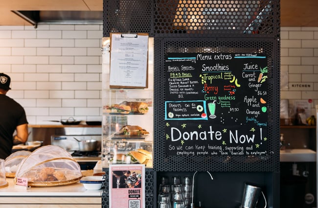 Close up of blackboard at not-for-profit cafe with 'donate now' written at the top