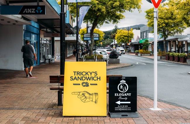 Sign on street with hand pointing in the direction of Tricky's Sandwich Co