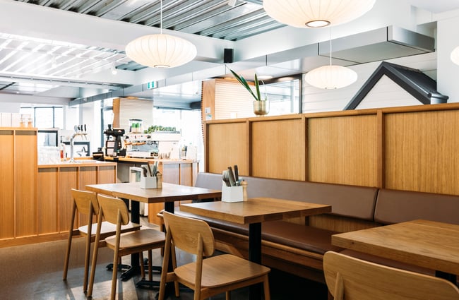 Contemporary scandi-inspired cafe interior with wooden tables, chairs and panelling