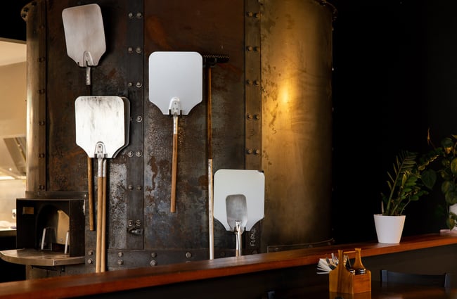 Metal pizza paddles hanging on wall at Two Thumb Harbourside