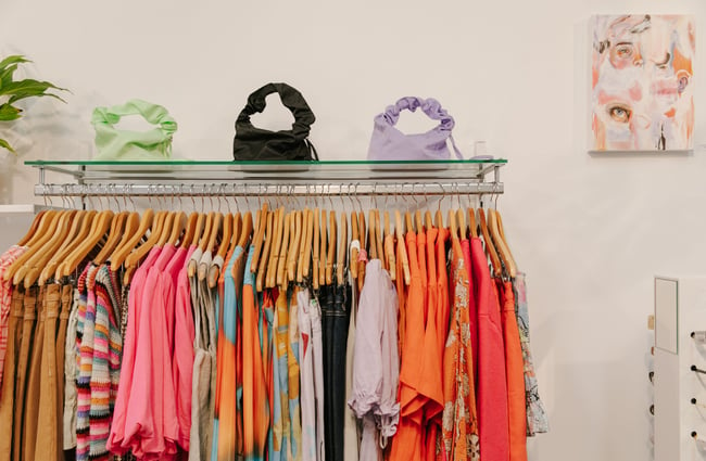 Orange and pink coloured clothes on display on a rack.