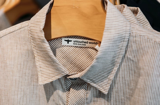 Close up of the Untouched World label inside a hanging striped shirt.