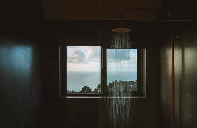 A shower inside a cabin with black painted walls.
