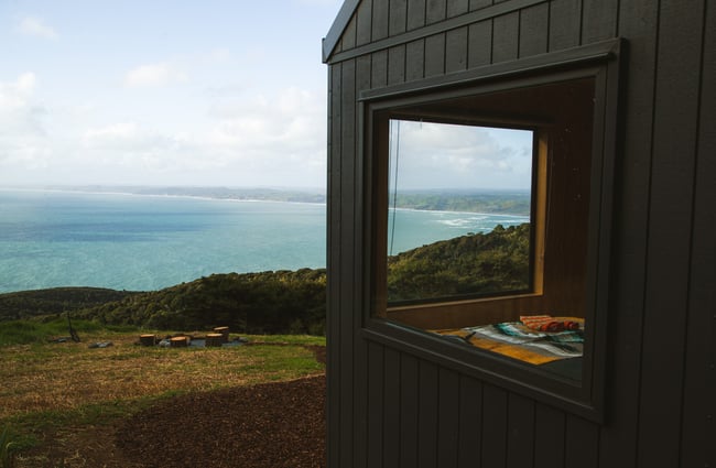 The corner of a black cabin overlooking the ocean.