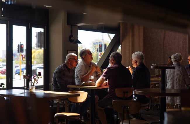 A group of customers sitting at a table in a darkly lit pub.