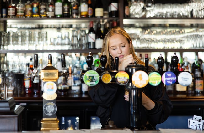 A female staff member pouring a pint of beer.