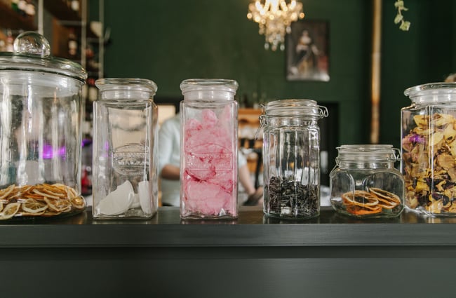 A close up of candy floss and bar snacks in large jars on the counter.