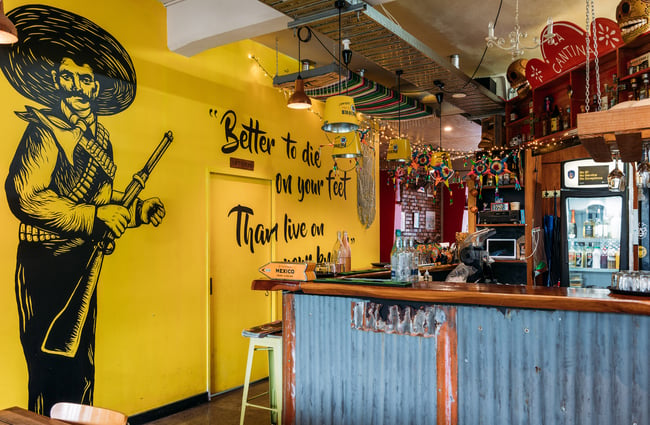 Illustration of a cowboy and text on yellow wall inside Mexican restaurant