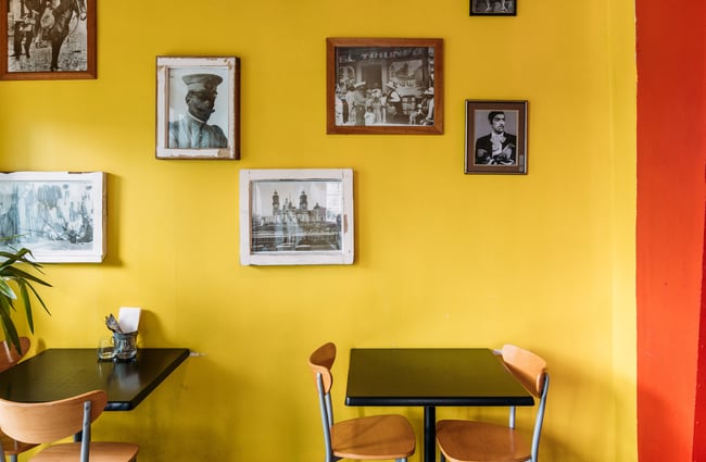 Dining table inside Mexican restaurant with old photographs on a bright yellow wall