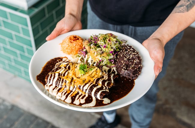 Plate of authentic Mexican dishes including Mole, enchiladas and rice