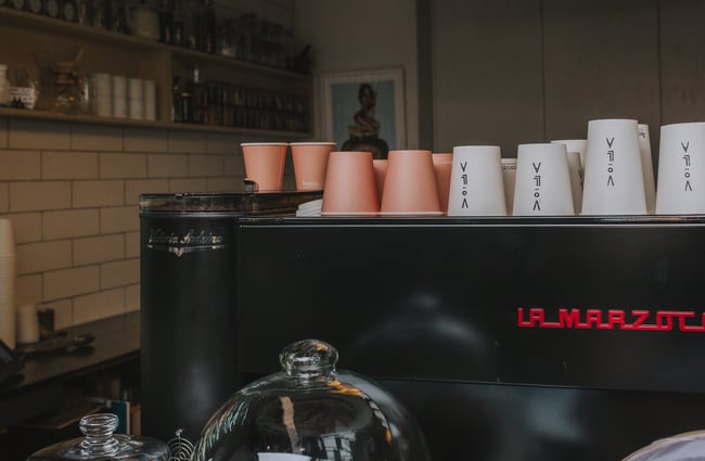 Cups on top of jet black coffee machine at Völla, Auckland.
