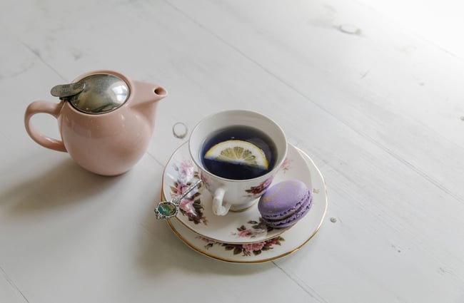 Lavender tea inside a pink teapot and a China cup and saucer.