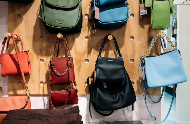 Colourful bags on a wall display inside a retail store.