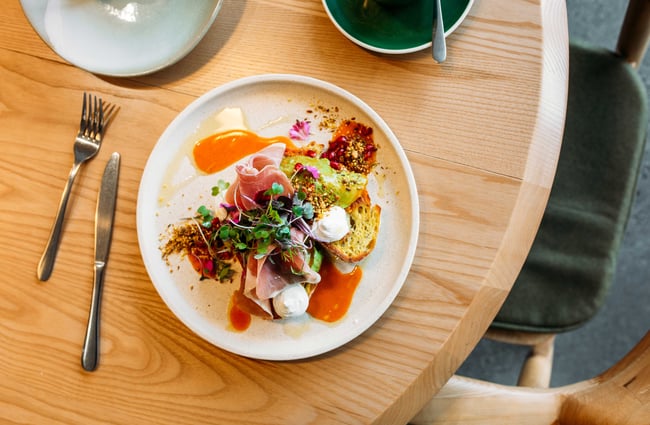 A flatlay of ham and eggs on toast on a wooden table.