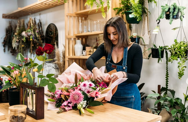 A woman putting together a bouquet of flowers.