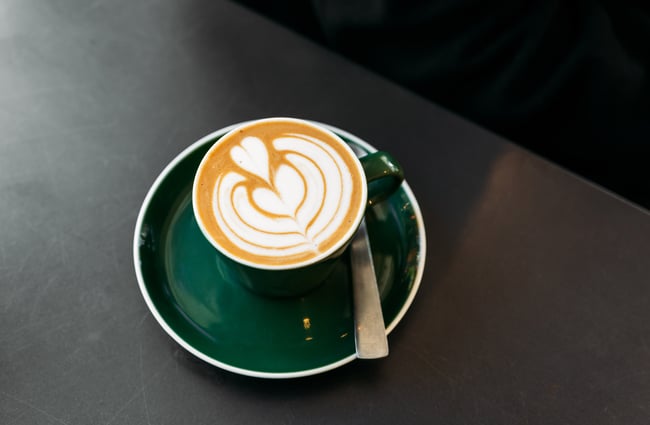 A close up of a flat white in a green cup.