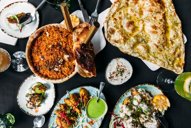 A flatlay of curries and naan on plates.