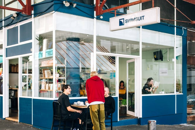 Exterior blue cafe with patrons eating outside.