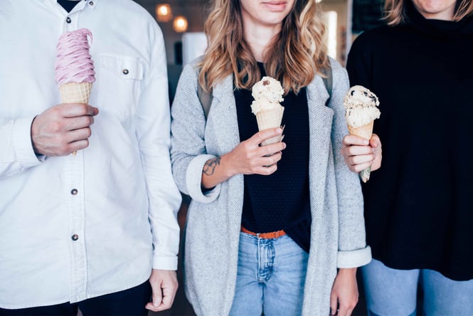 Two women and a man holding an ice cream cone each, their heads cut out of the photo.
