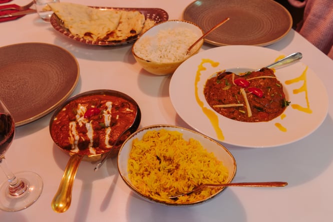 Indian food on plates in a dimly lit restaurant.