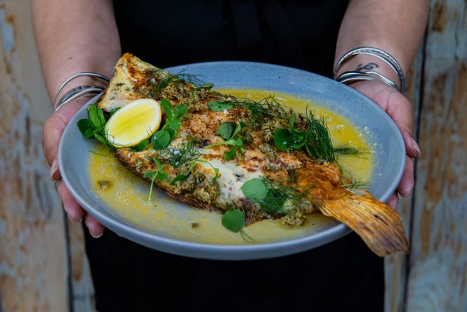 Whole fish with lots of herbs on a plate at Kokomo in Christchurch