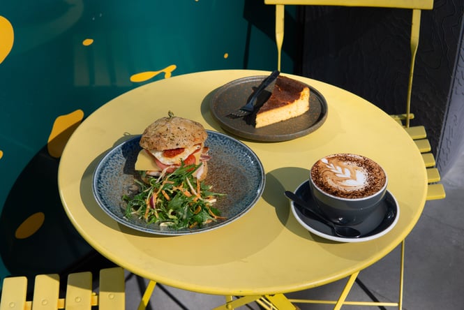 Sandwich, cake and coffee on a yellow cafe table