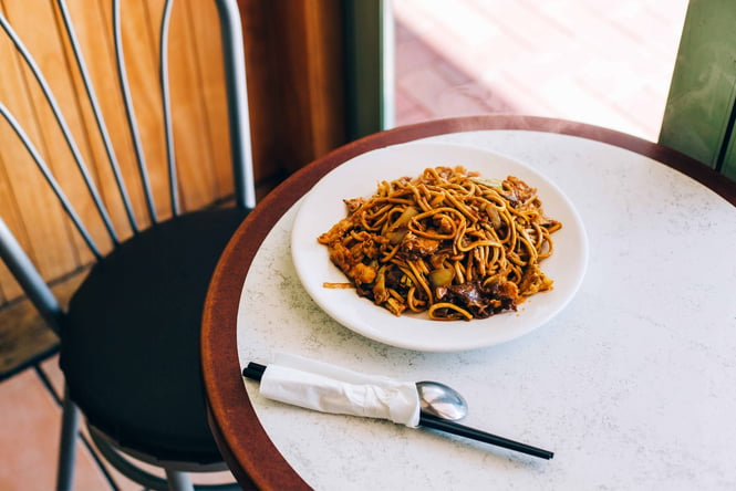 A plate of noodles on a white table near a window.