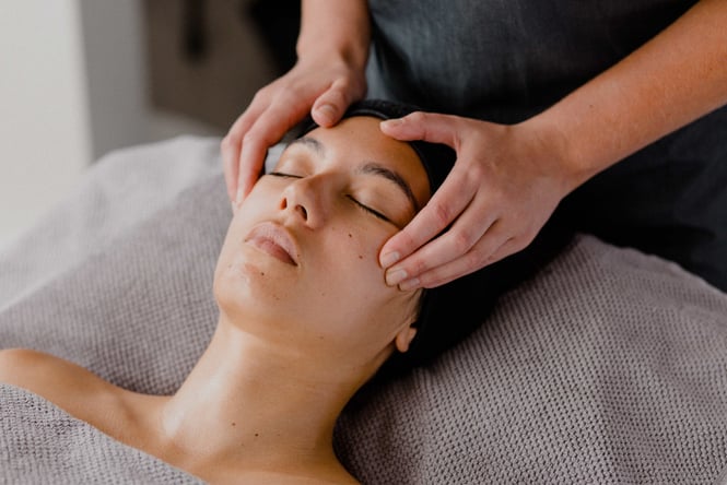 A woman closing her eyes whilst receiving a facial.