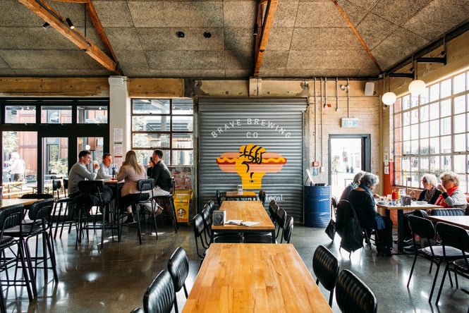 People dining at high tables inside Brave Brewing Co.